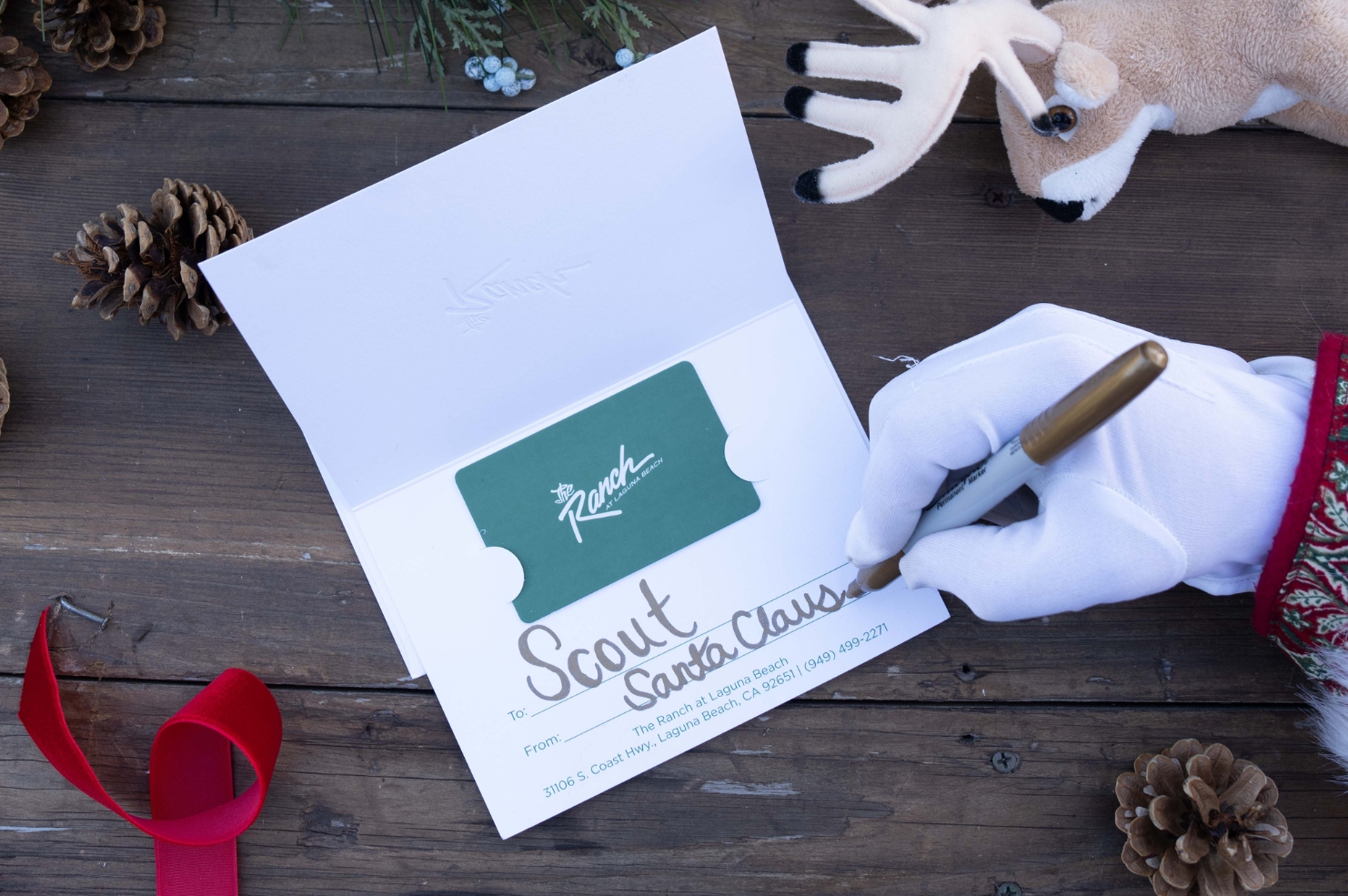 Santa signing his name on a holiday gift card.