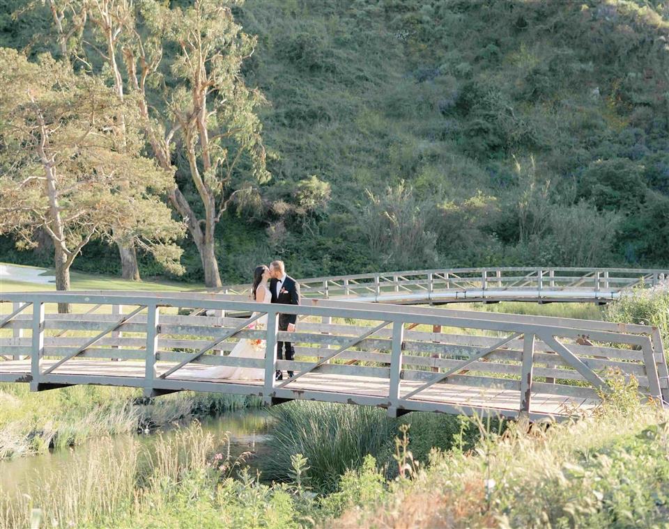 Bride and Groom kissing on a bridge